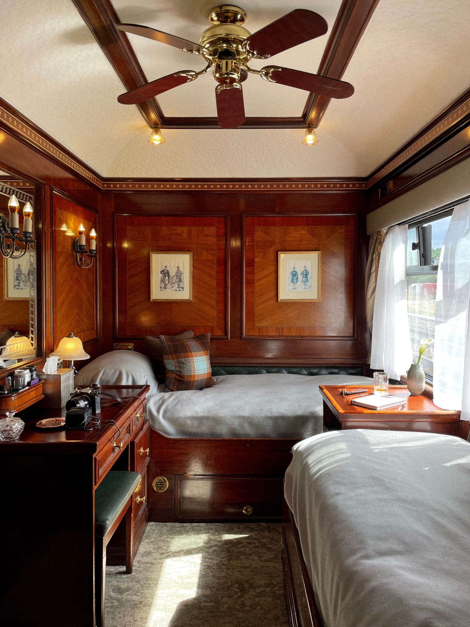A Royal Scotsman cabin interior — Edwardian-style mahogany marquetry and the picture window framing Scotland beyond.