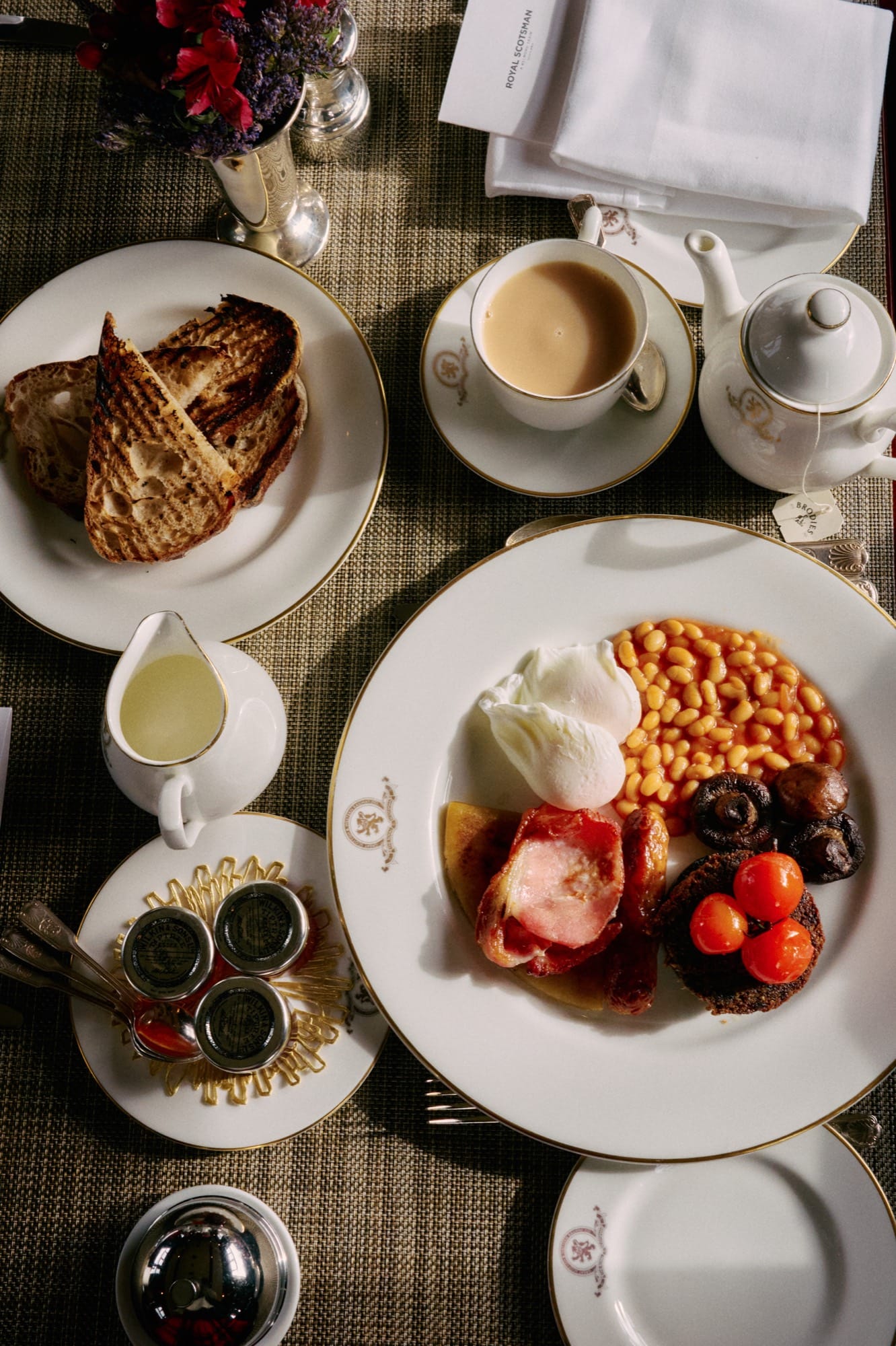 A dining service aboard Royal Scotsman — plated cuisine on heritage tableware, the marquetry of Raven or Swift visible in the background.