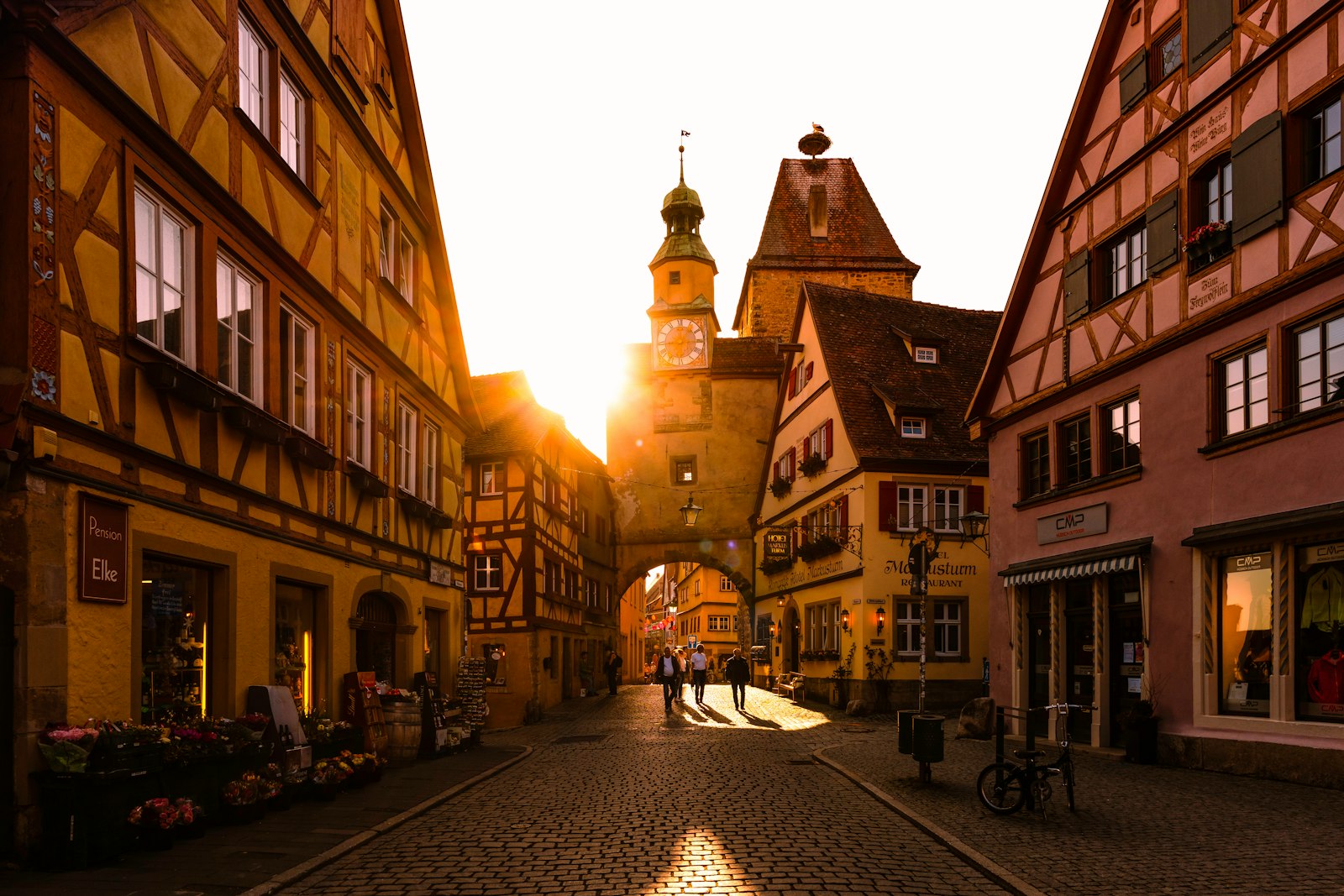 A sunlit medieval street of half-timbered houses in an old European town.