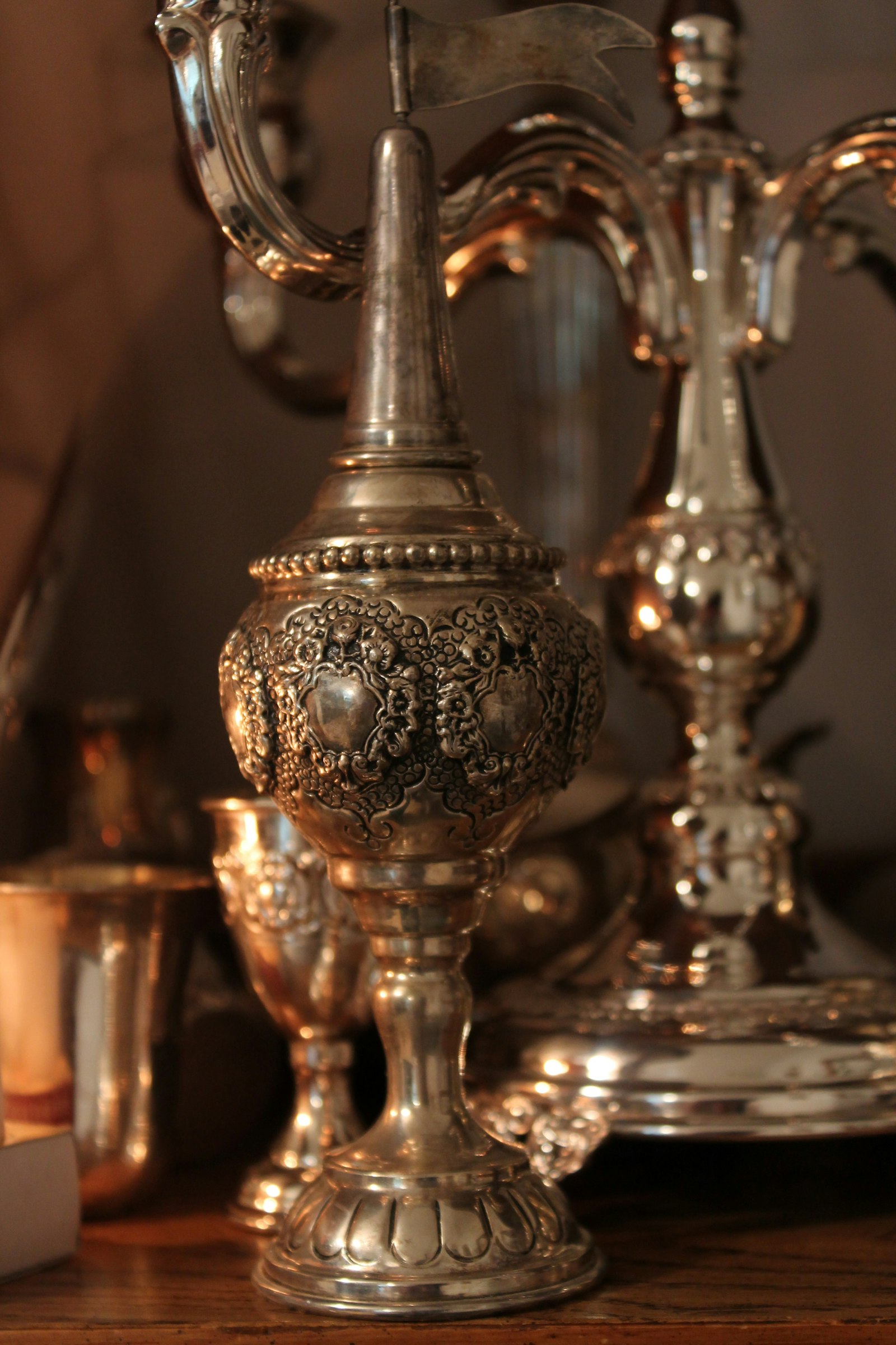 A silver candelabra and candles on a wooden table, lit in low evening light.