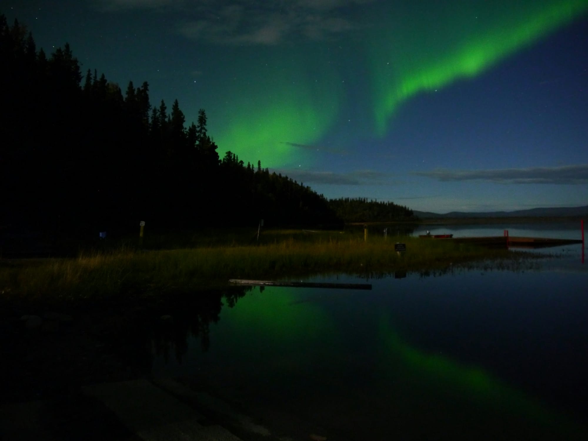 Aurora borealis reflected in still water at night.