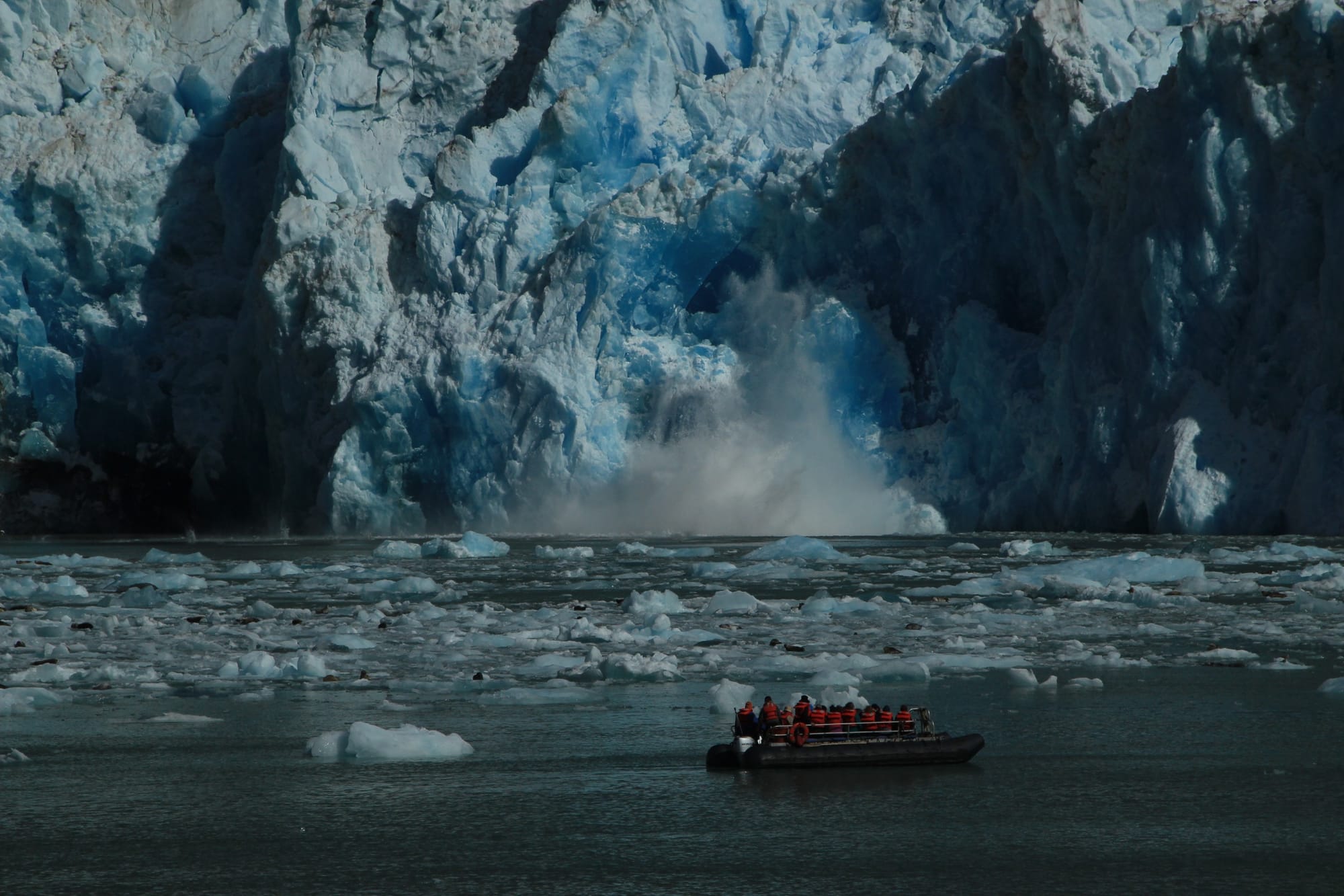Calving glacier at Dawes Glacier with an UnCruise skiff in the foreground — Alaska Inside Passage.
