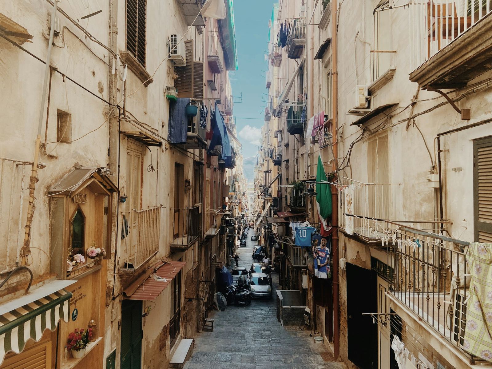 A narrow alley in the old town of Naples with laundry strung between the buildings.