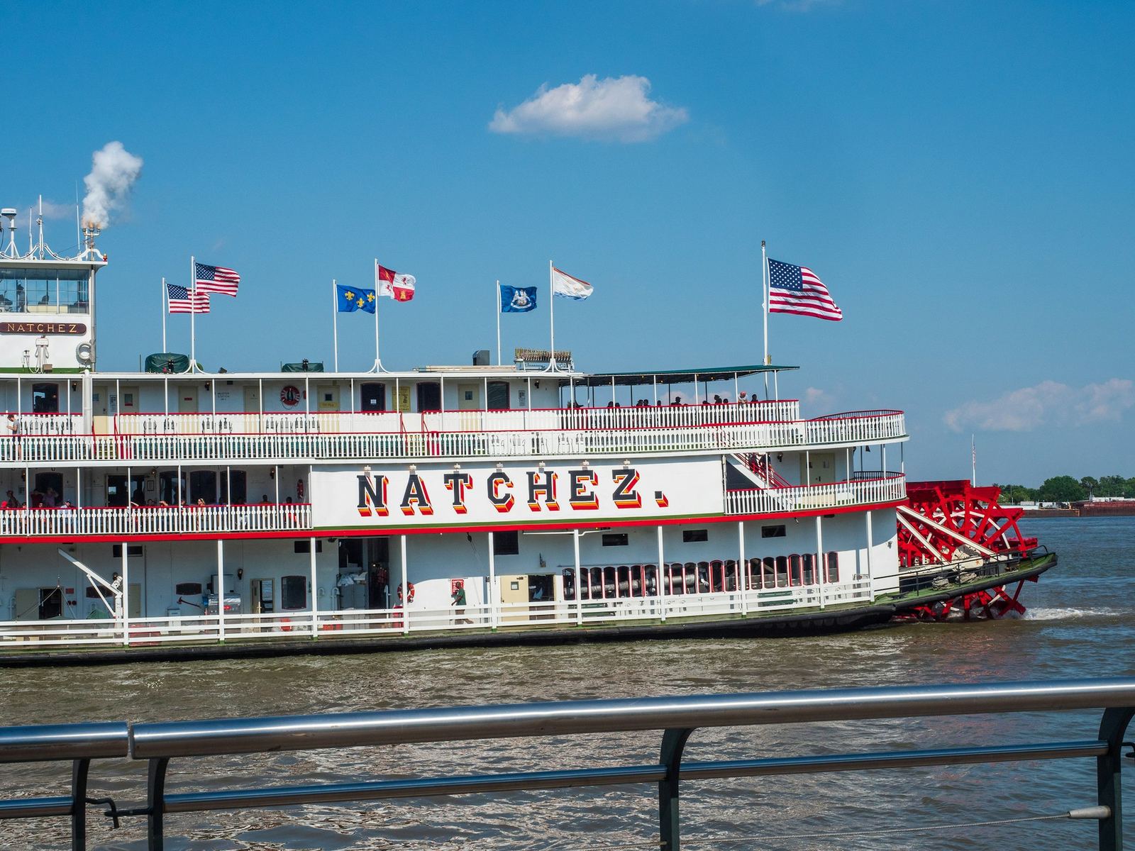 The paddlewheeler Natchez on the Mississippi River under a bright sky.