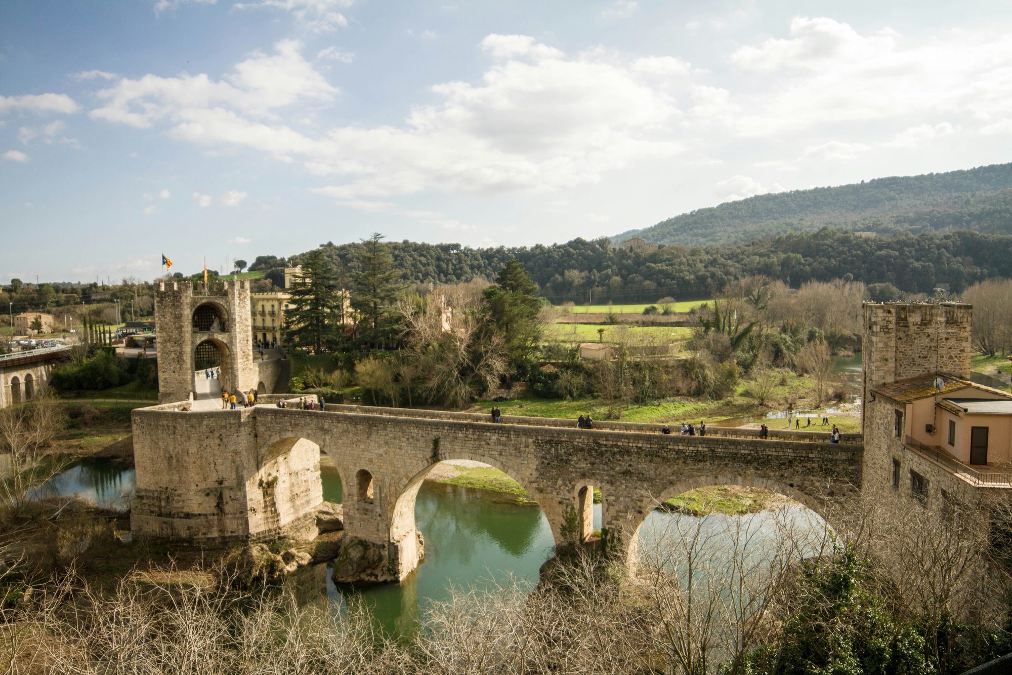 Besalú's fortified medieval Romanesque bridge crossing the Fluvià river toward the stone town.