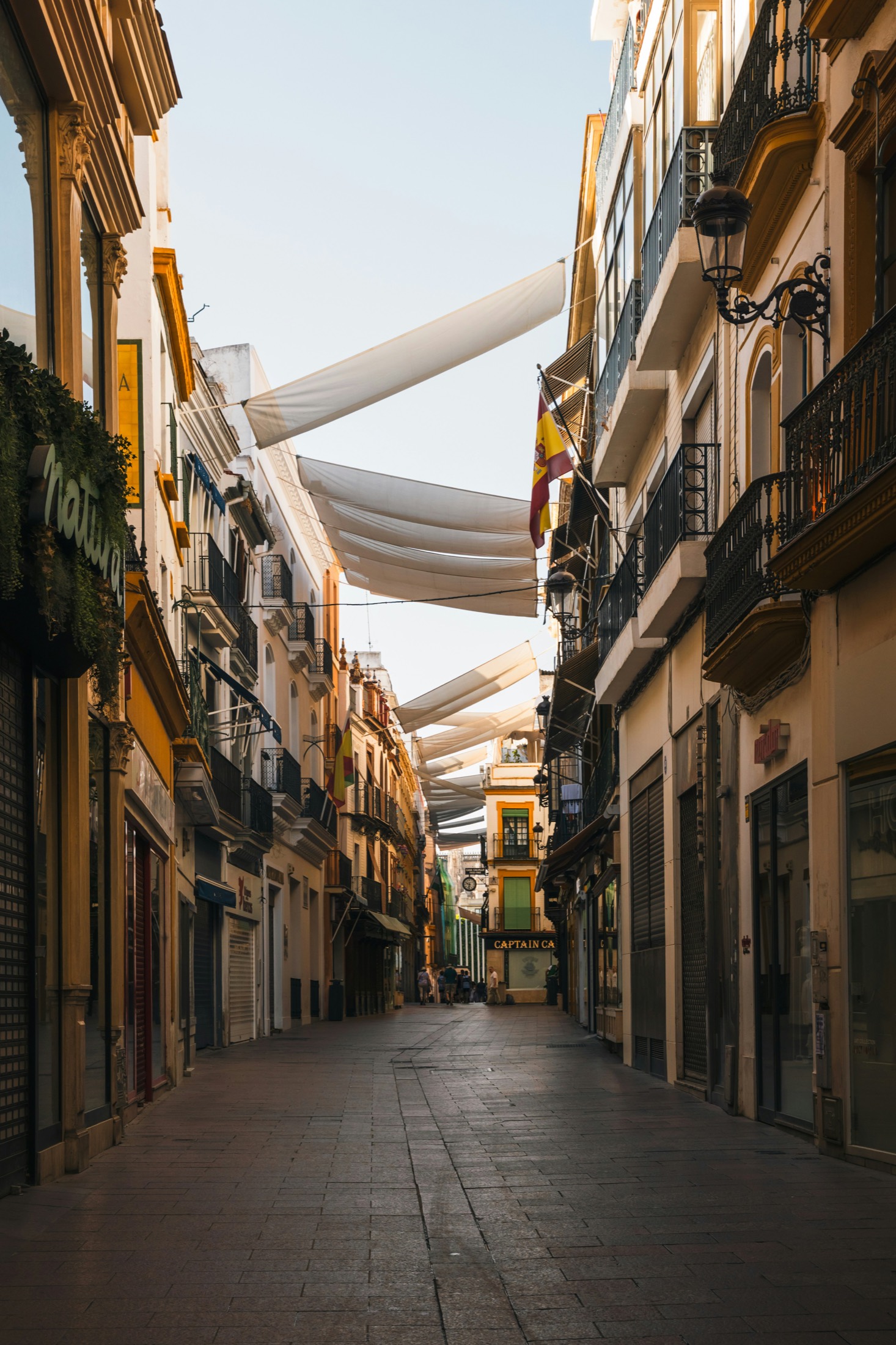 A narrow lane in Seville's Barrio de Santa Cruz, shaded by fabric canopies strung between the buildings.
