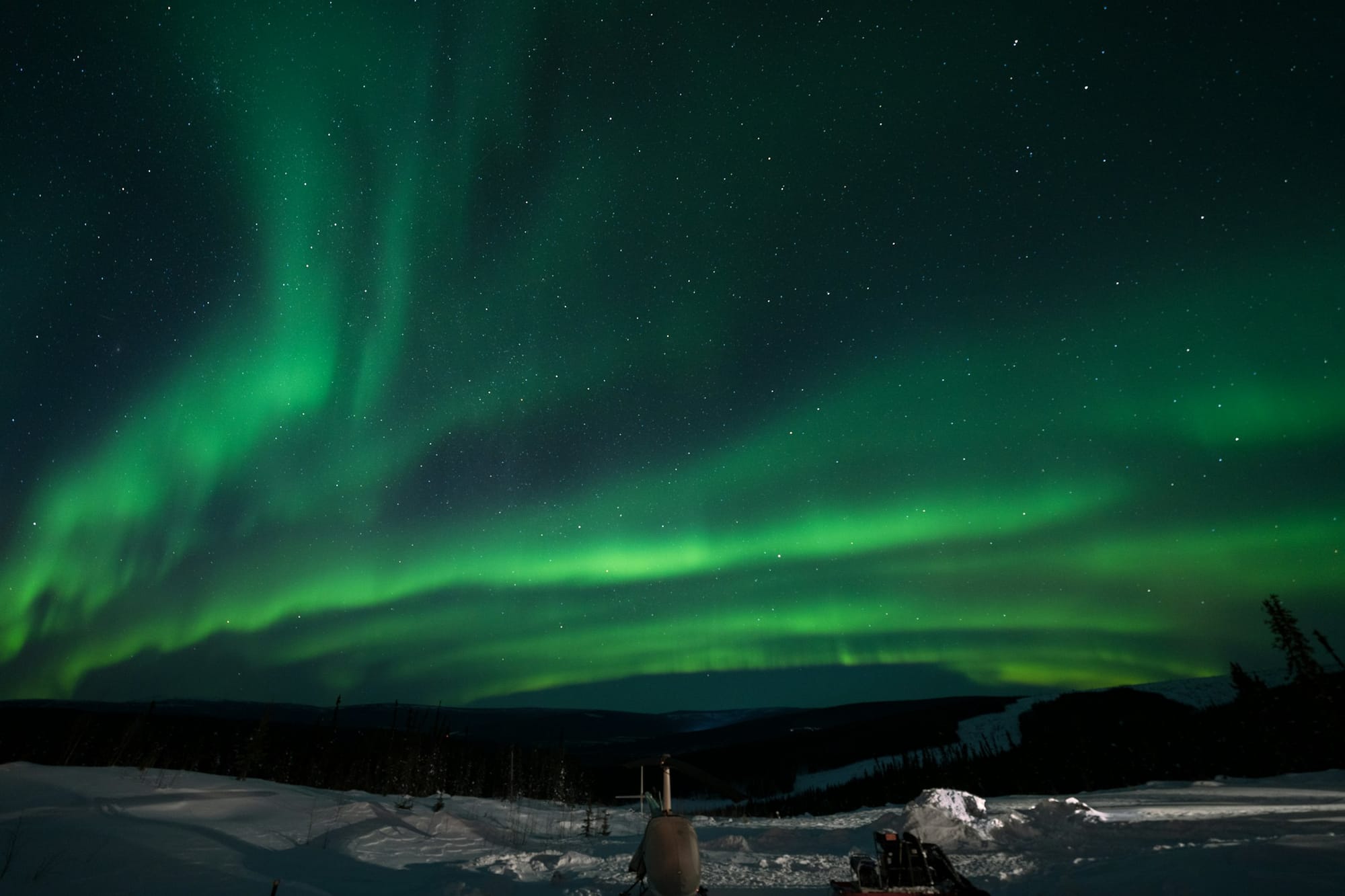 Purple and green aurora over snowy Alaska landscape.