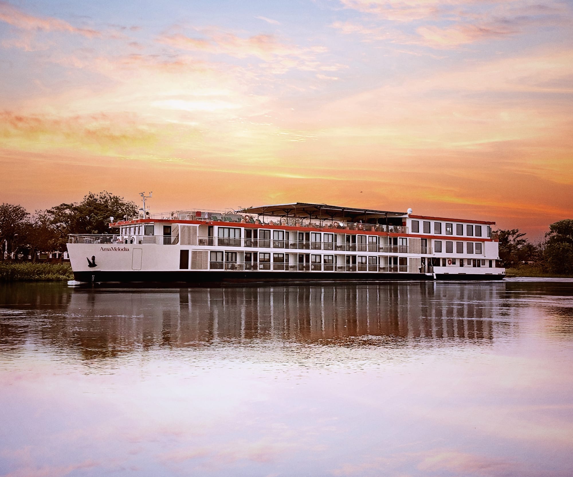 AmaMelodia, one of AmaWaterways' two 60-guest Magdalena river ships, mirrored in the water at sunset.