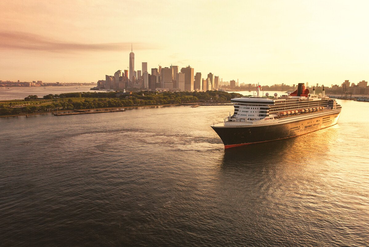 Queen Mary 2 departing New York City at golden hour, the Manhattan skyline behind her
