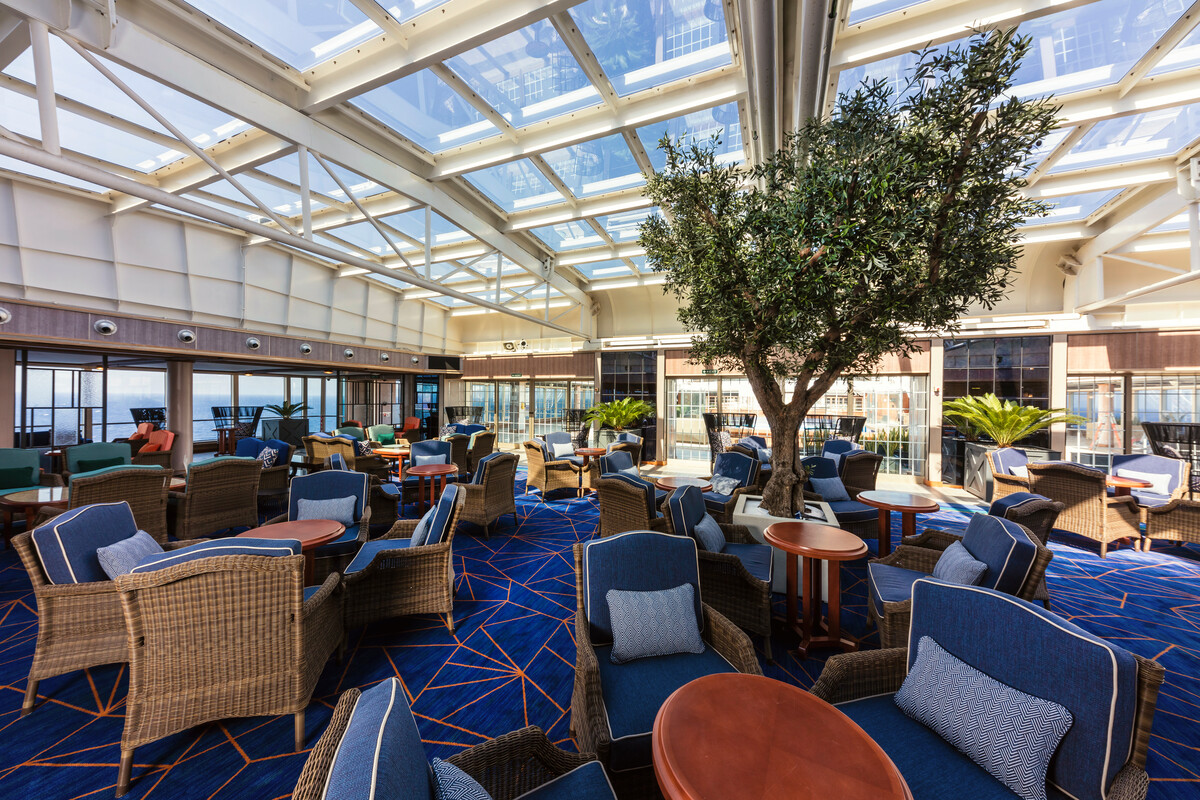 Queen Victoria's Winter Garden — glass-roofed, plant-filled, the ship's calmest daytime room.