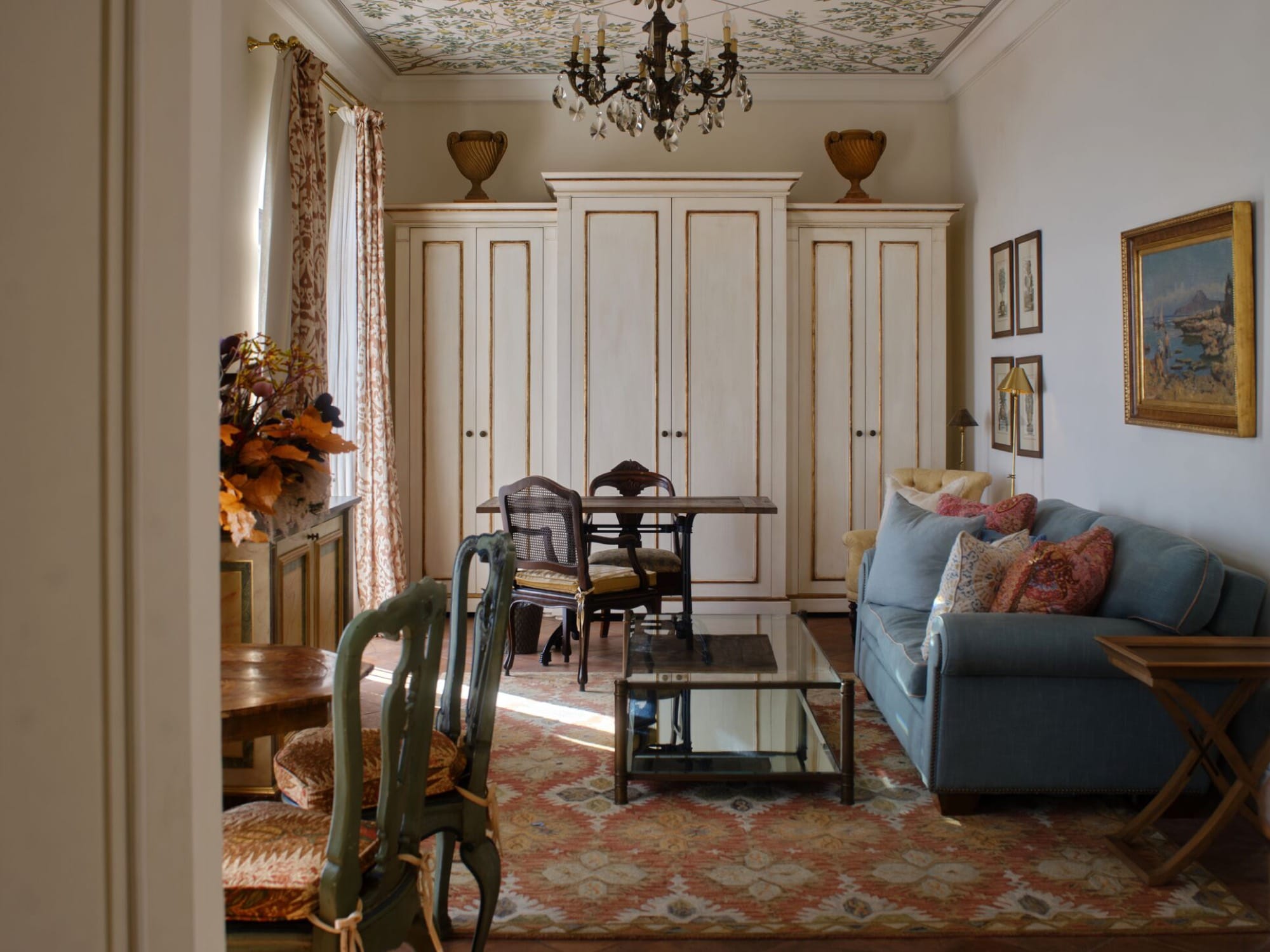 A historic-wing suite living area at the Caruso — frescoed ceiling, crystal chandelier, blue sofa, antique furniture on a patterned rug.
