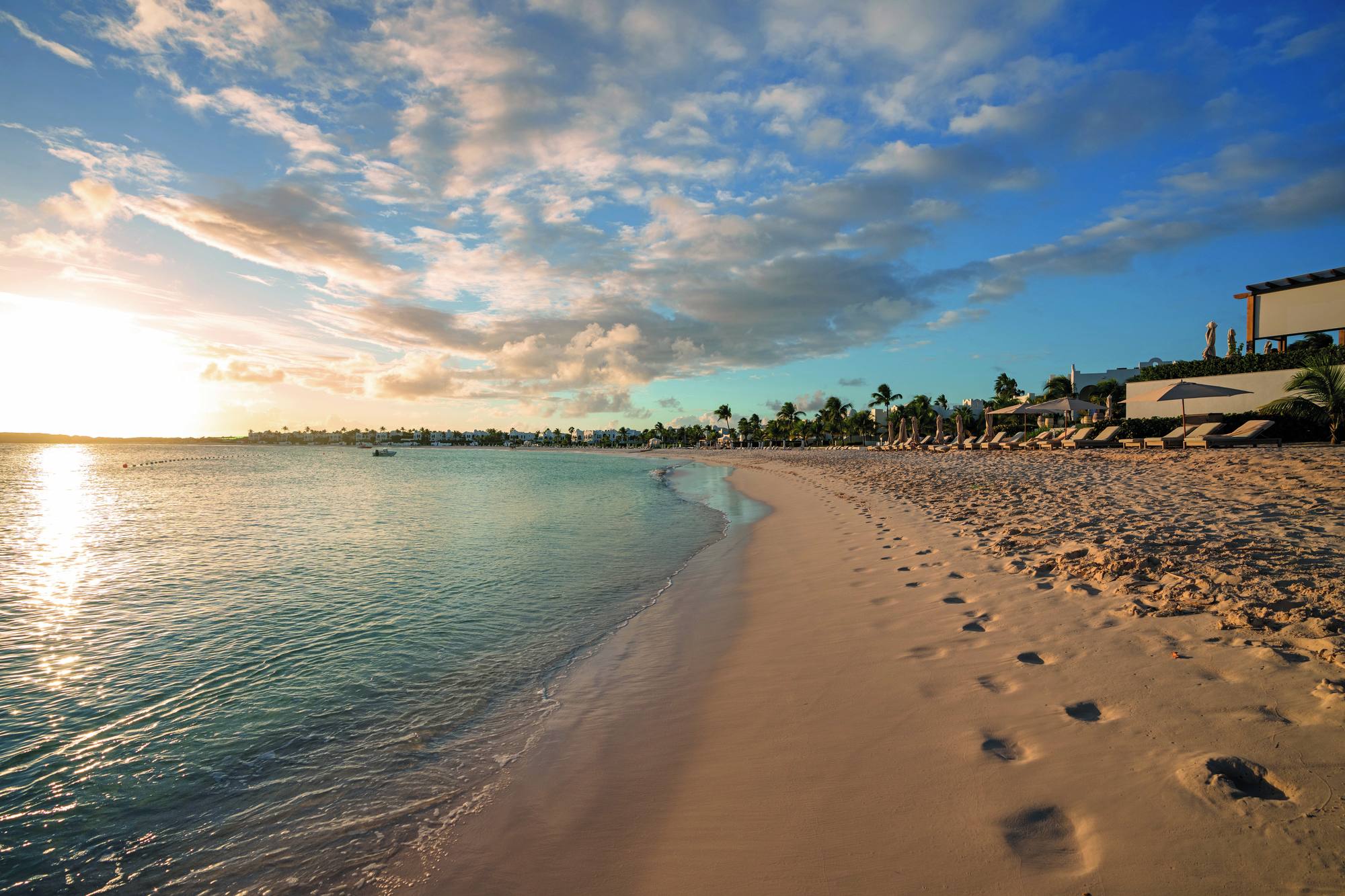 Golden-hour light over Maundays Bay at Cap Juluca, the resort's white cottages along the shore.
