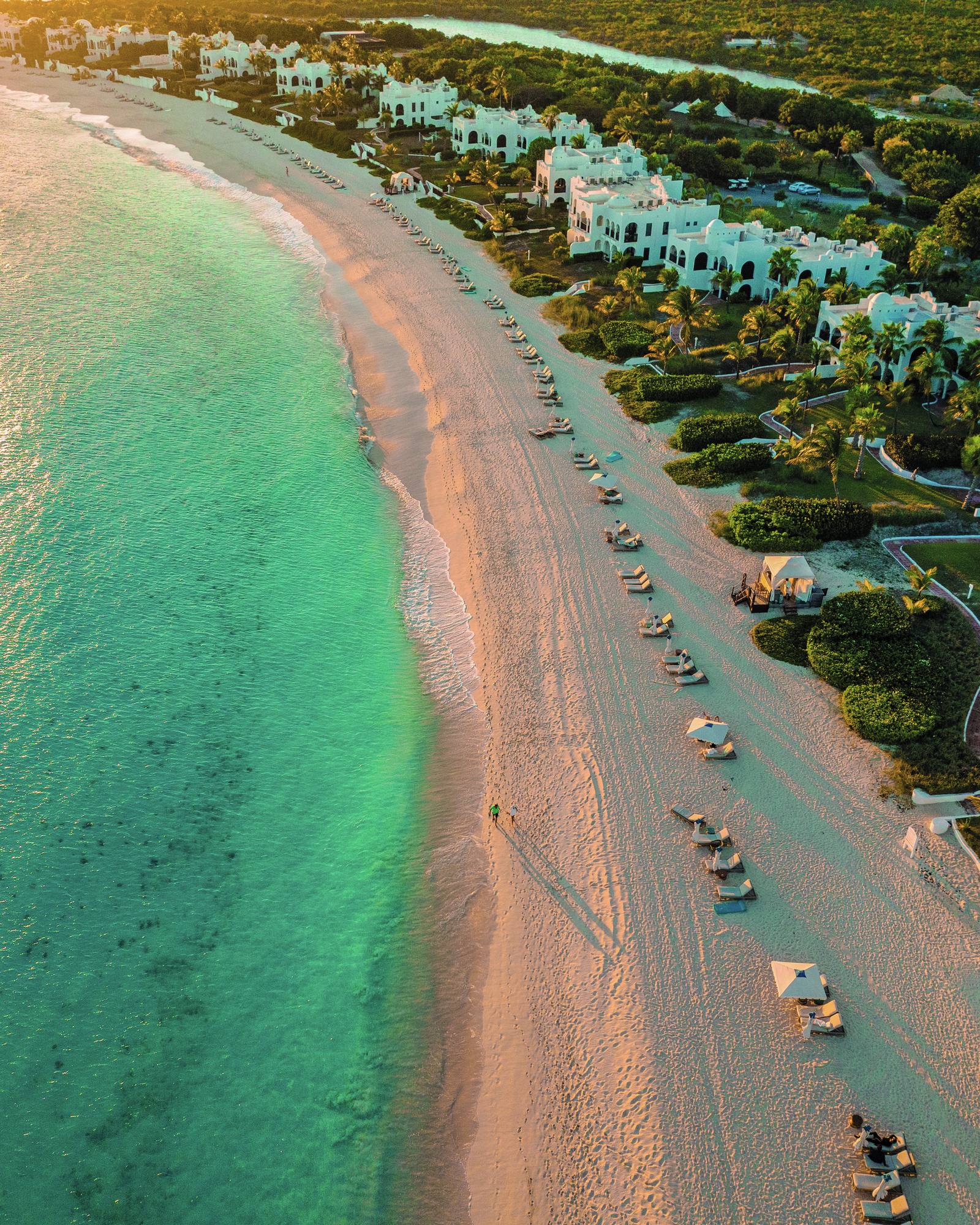 Aerial view of the mile-long Maundays Bay beach at Cap Juluca, loungers and umbrellas dotting the sand.