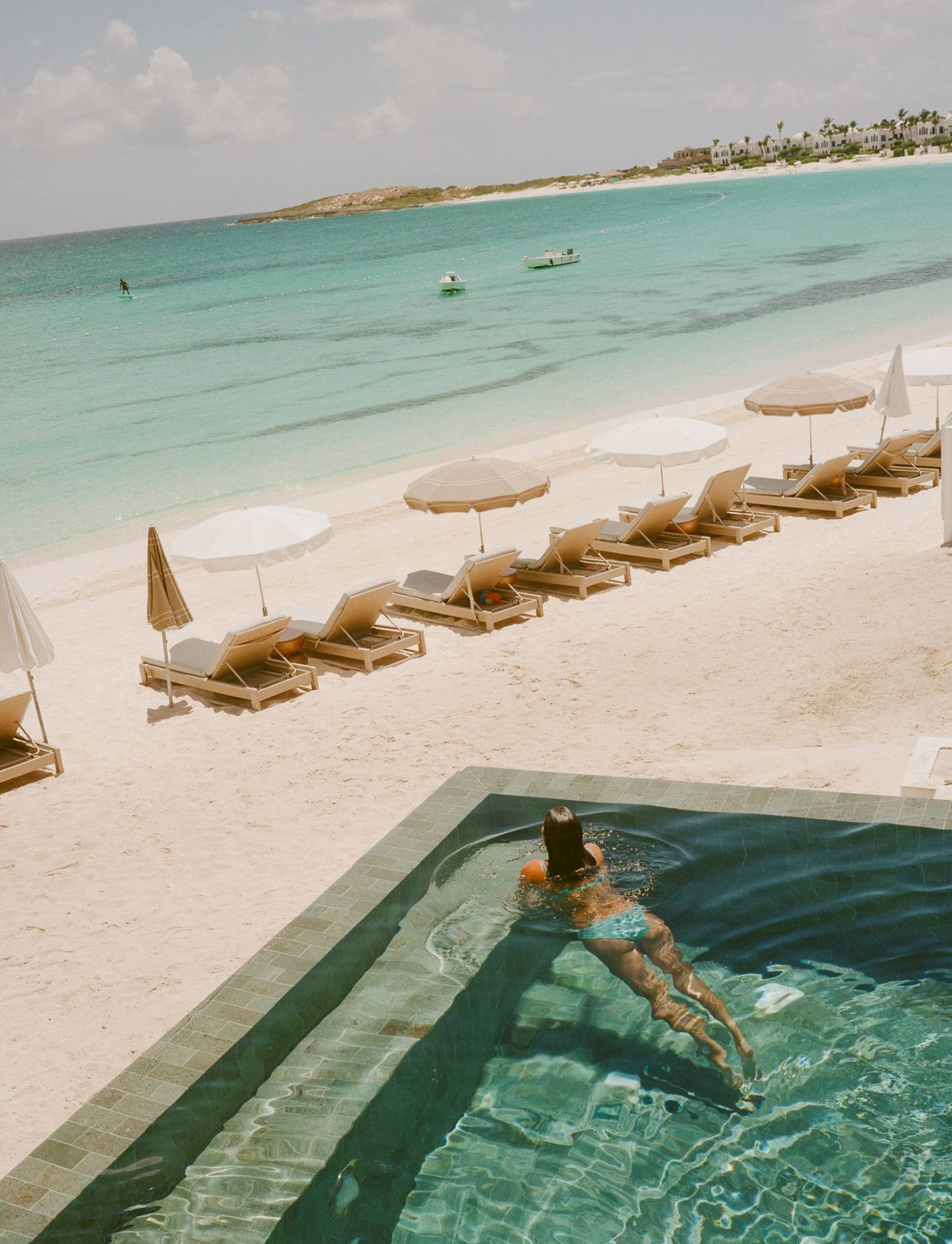 A swimmer at the edge of the infinity pool overlooking the beach and loungers at Cap Juluca.