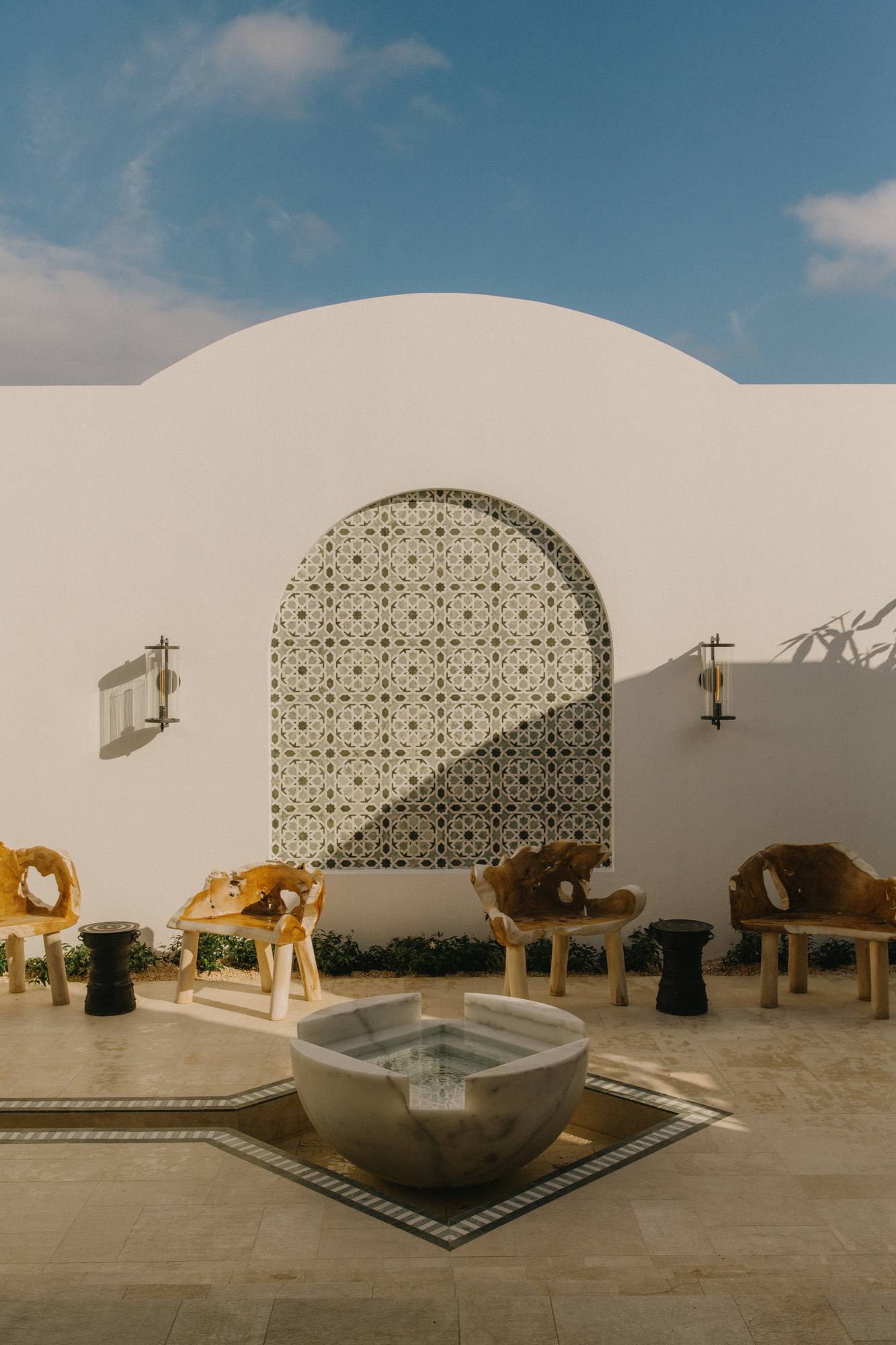 An arched, tiled alcove and a stone fountain in a serene courtyard at the Cap Juluca Spa by Guerlain.