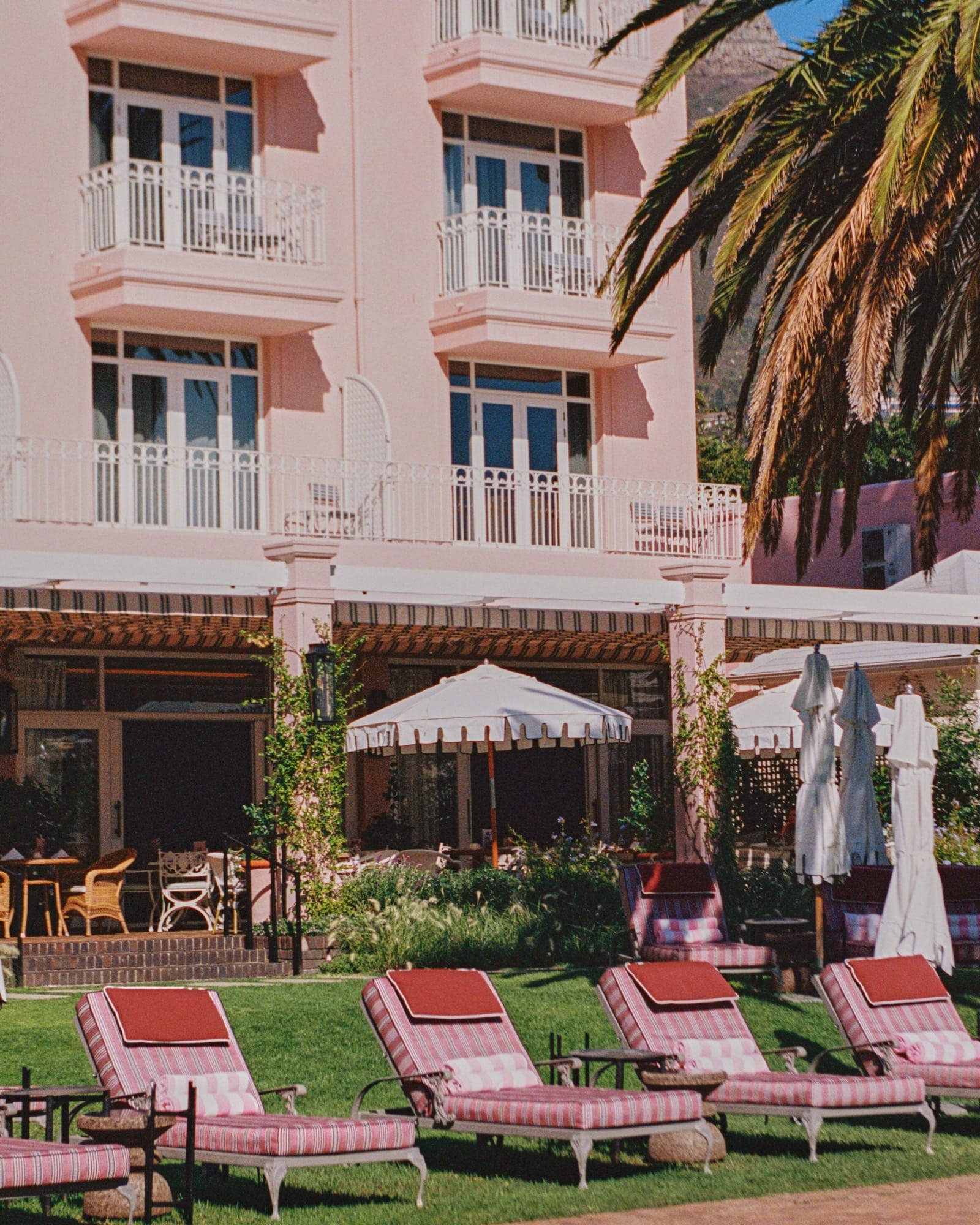 Pink-striped loungers on the lawn below Mount Nelson's pink facade and balconies