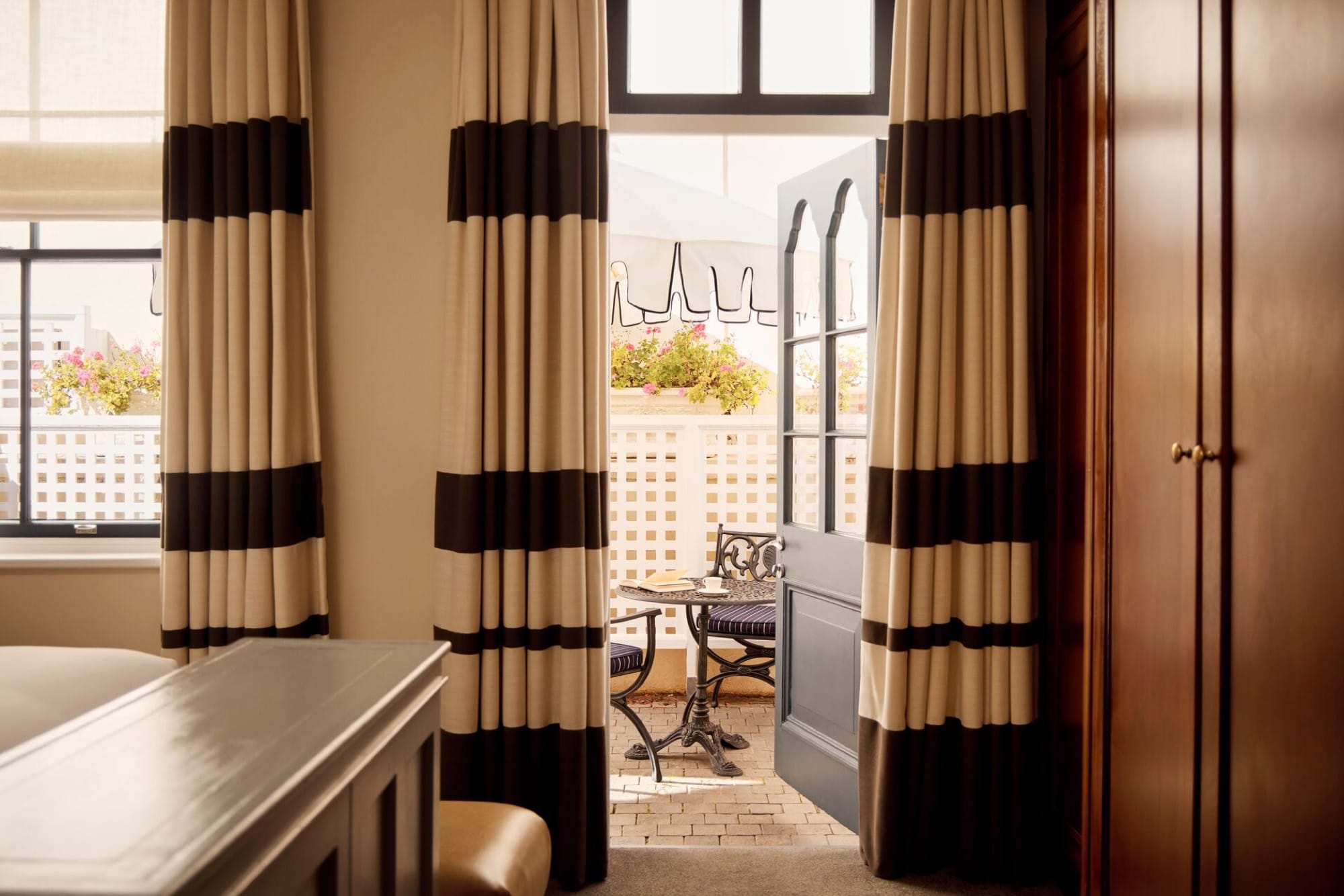 A Mount Nelson living area — long sofa, antique side tables, garden doors open to the grounds.