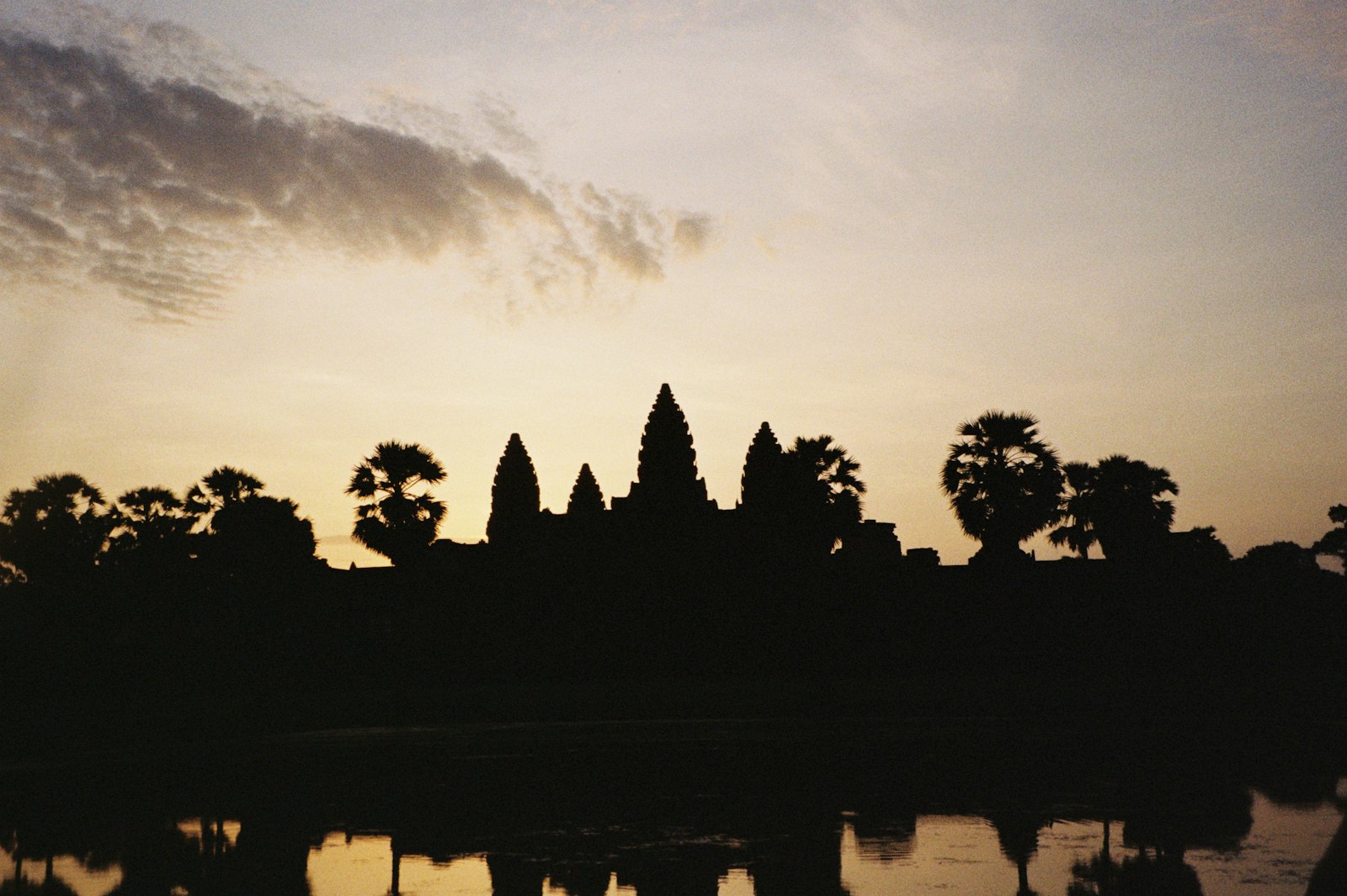 Cambodia — Angkor Wat silhouetted at sunrise, reflected in the moat