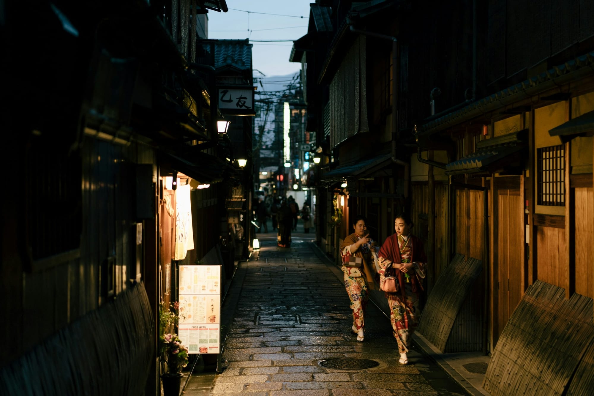 Japan — lantern-lit Kyoto alley at dusk, two women in kimono