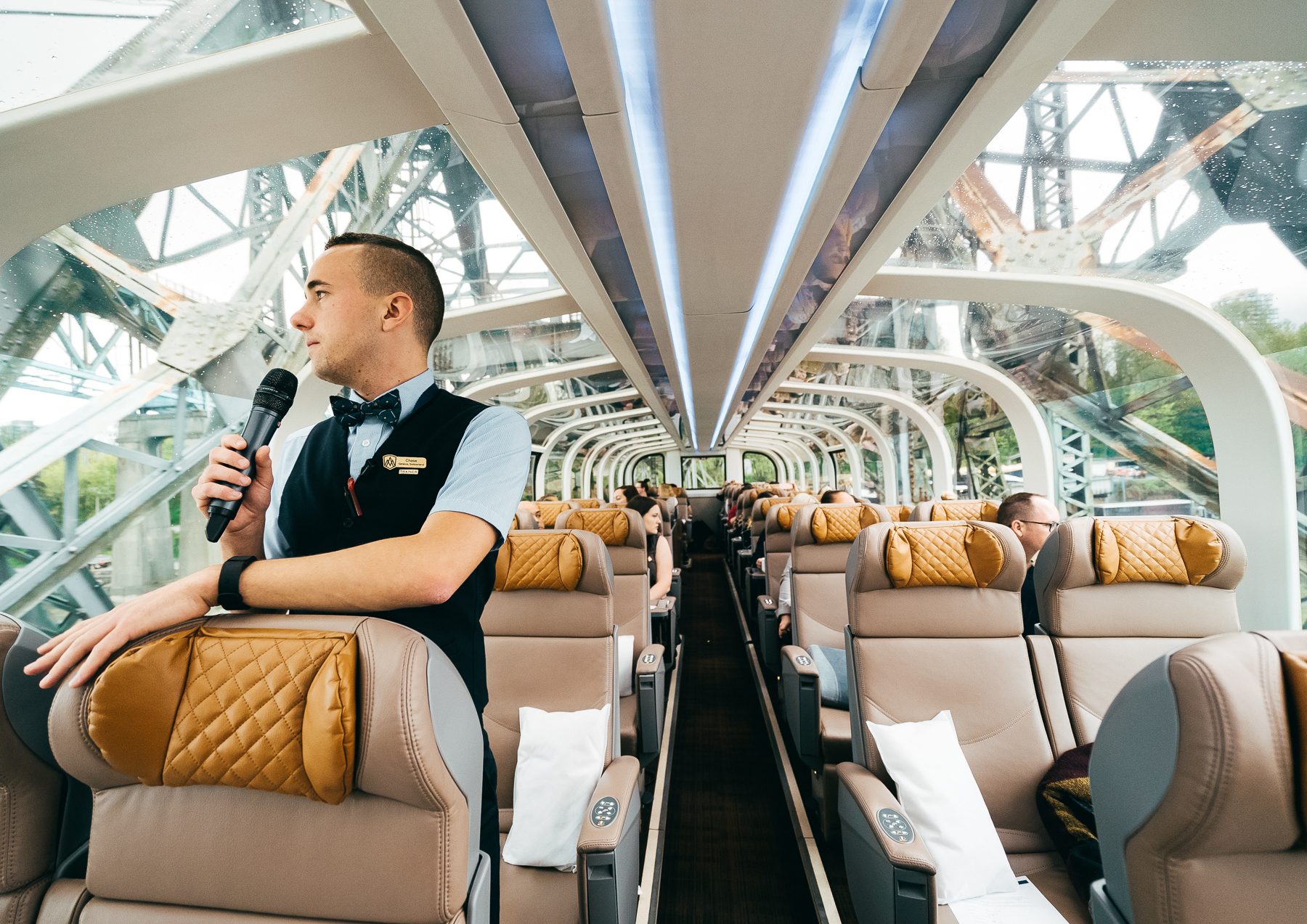 An onboard host shares commentary in the upstairs GoldLeaf glass-dome coach, guests seated beneath the curved dome windows.