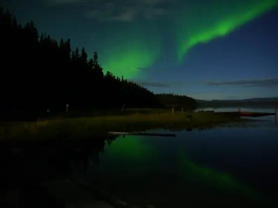 Aurora borealis reflected in still water at night.