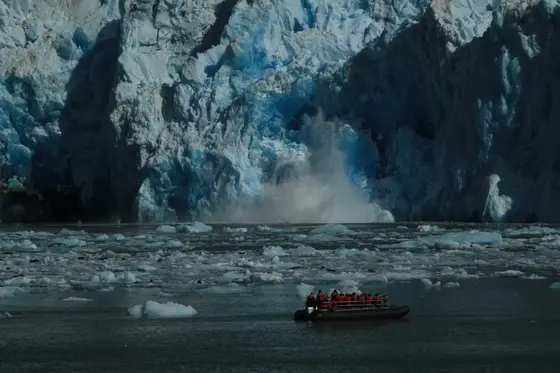 Calving glacier at Dawes Glacier with an UnCruise skiff in the foreground — Alaska Inside Passage.