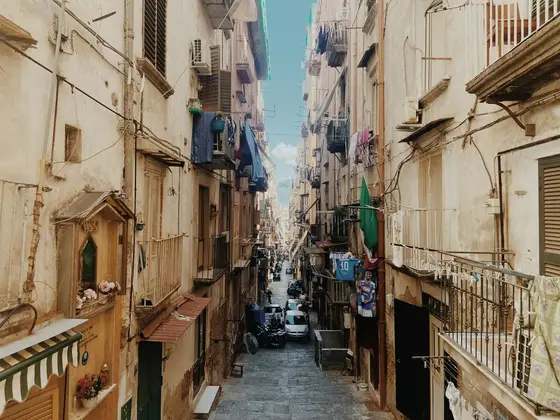 A narrow alley in the old town of Naples with laundry strung between the buildings.