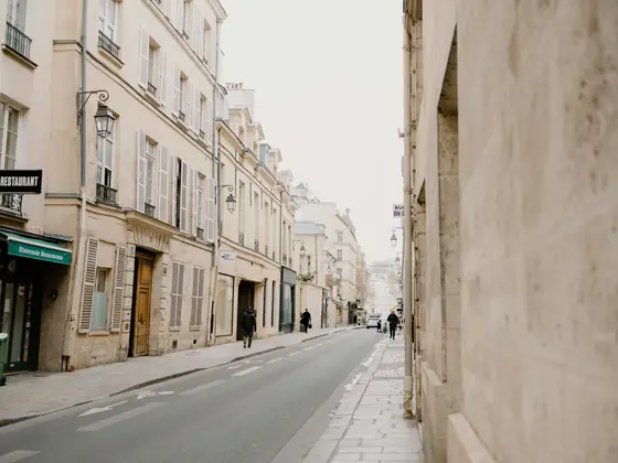 A quiet Left Bank street in Paris in pale early light, shutters closed, no one about.