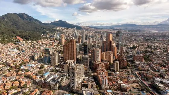 Colorful buildings of the historic Candelaria district below green Andean hills in Bogota