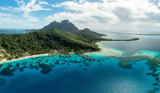 Overwater bungalows over a turquoise lagoon with Mount Otemanu behind in Bora Bora