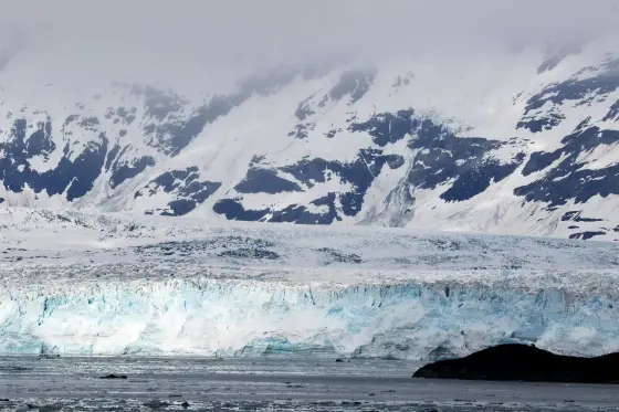 A tidewater glacier meeting the sea beneath snowy peaks in Glacier Bay, Alaska