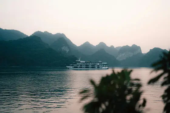 A cruise ship among the limestone karsts of Halong Bay at golden hour, Vietnam