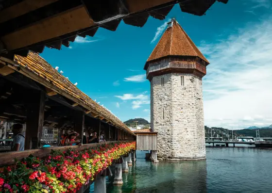 The wooden Chapel Bridge over the Reuss River with mountains behind in Lucerne, Switzerland