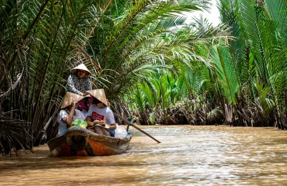Palm-lined banks and a wooden boat on the Mekong River in Southeast Asia