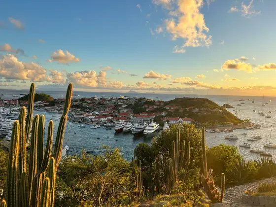 Yachts anchored in a turquoise harbor below green hills on St. Barths