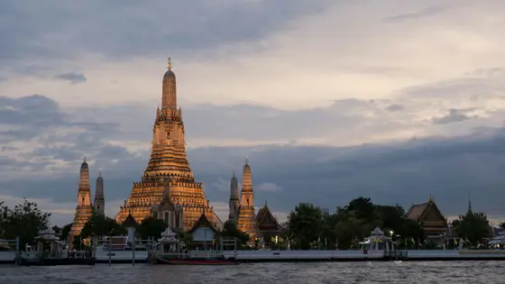 The spires of Wat Arun rising above the Chao Phraya River at dusk in Bangkok, Thailand
