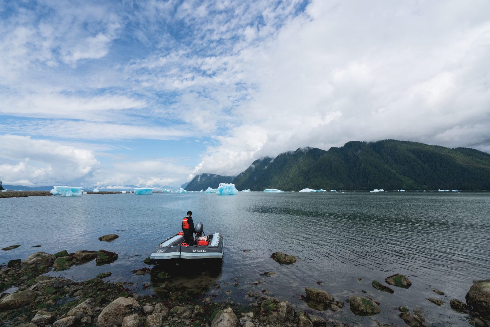 A skiff carrying guests through the LeConte ice gardens — small chunks of glacial ice in still Southeast Alaska water.