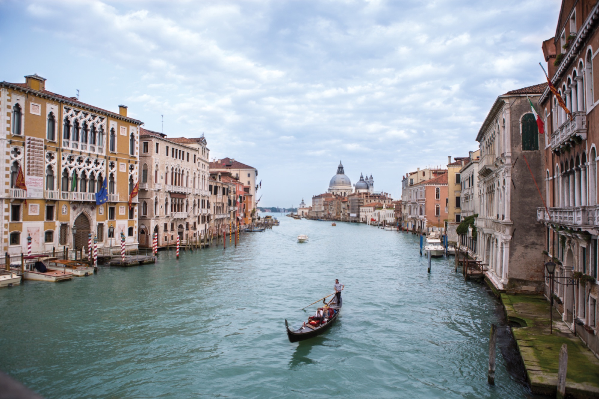 A gondolier poles down the Grand Canal toward the domes of Santa Maria della Salute, palazzi lining both banks.