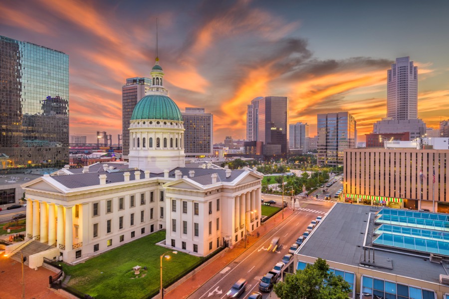 The green dome of the Old Courthouse in St. Louis lit at sunset, downtown towers rising on either side.