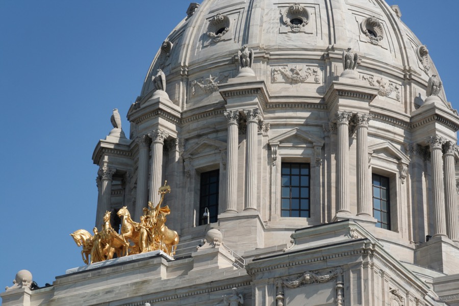 The white dome and gilded quadriga of the Minnesota State Capitol in St. Paul against a clear sky.