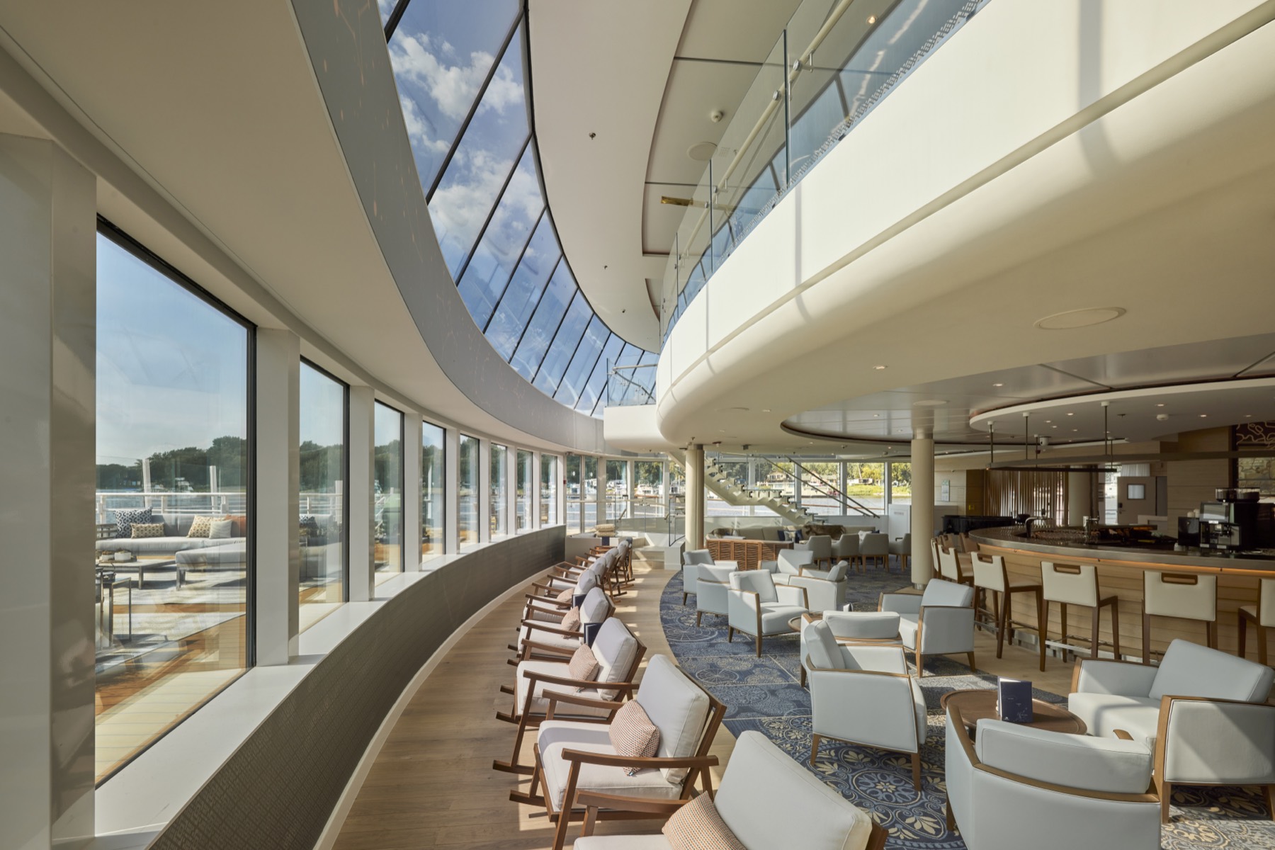 The Explorers' Lounge aboard the Viking Mississippi — a curved two-storey wall of glass along pale armchairs, the river bright outside.