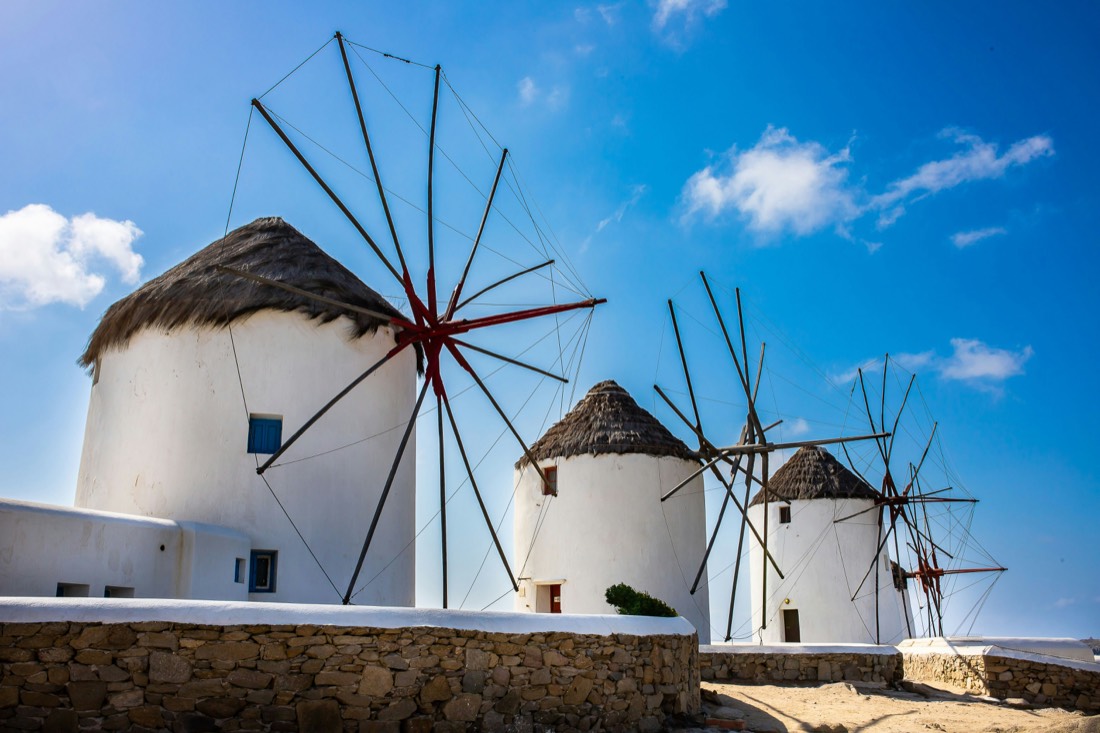 The whitewashed windmills of Mykonos against a bright Aegean sky.