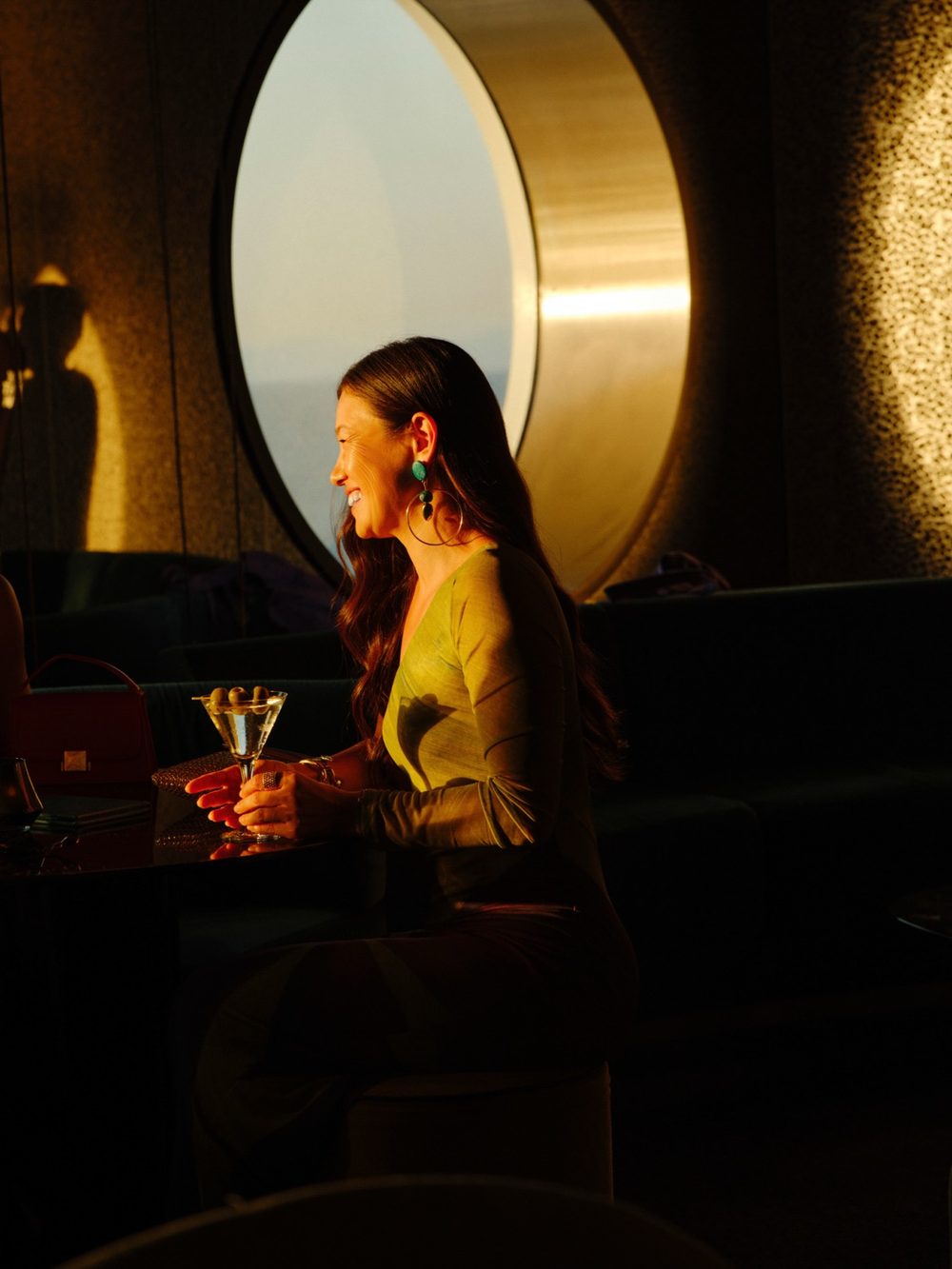 A guest lingering over a martini in the golden light of On The Rocks, aboard a Virgin Voyages ship.